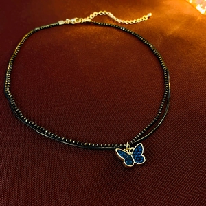 Detail of double-layer black choker with navy blue butterfly pendant and gold lobster clasp