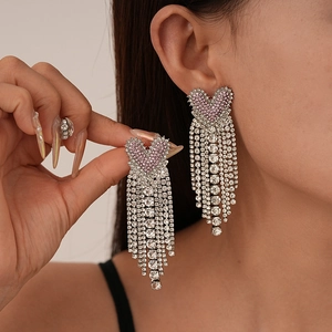 Elegant heart-shaped tassel earrings with pink zircons and silver finish on female model