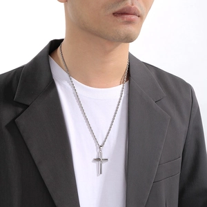 Close-up of a silver minimalist cross pendant with twisted metal chain on a model