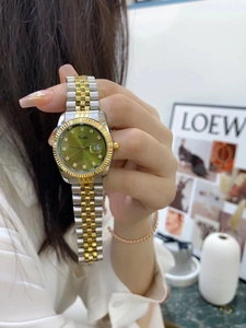Detail of green dial ladies watch with calendar and gold steel band