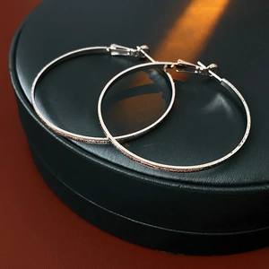 Macro detail of silver-plated large hoop earrings with matte textured finish on black leather