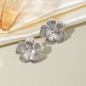 Macro detail of silver flower earrings with radiant petal texture and metallic finish