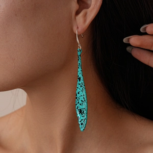 Close-up of bohemian turquoise waterdrop earrings with black paint splatter on model