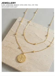 Dettaglio di una collana doppia dorata con ciondolo a moneta occhio su pietra