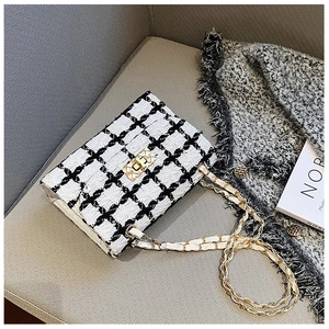 Close-up of black and white tweed texture with golden chain strap on a crossbody bag