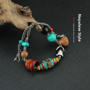 Detail of handmade ethnic bracelet with turquoise beads and tassel on wooden stand