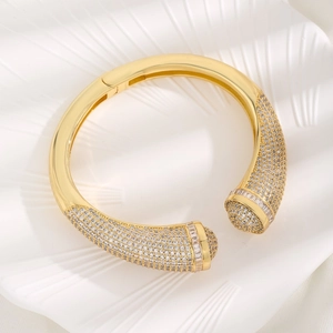Luxurious gold-plated open bangle with micro-pave cubic zirconia on a white wavy background