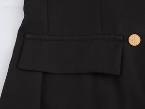Detailed view of gold button and pocket on black double-breasted blazer dress
