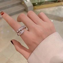 Detailed view of silver snake-head ring with white stones on a hand worn model