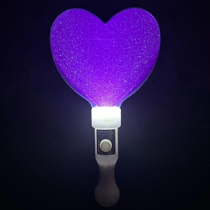 Close-up of glowing purple heart LED stick with white handle and button instructions