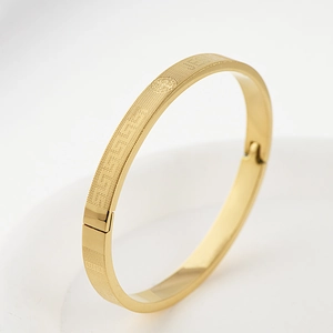 Detail view of gold titanium bracelet with Greek key pattern and Saint Benedict medal