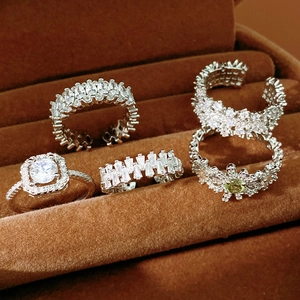 Detail of five silver rings with white and green zircons in a brown jewelry box