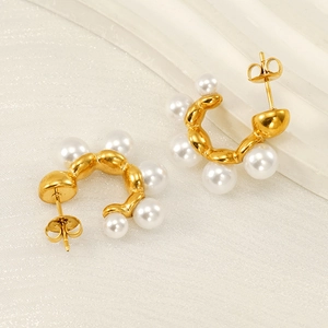 French vintage gold C-shape wave earrings with white pearls on a soft beige background