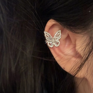 Close-up of a sparkling butterfly ear cuff with cubic zirconia on a model's ear.