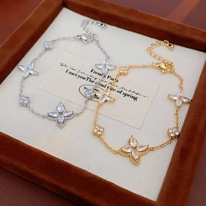 Macro detail of gold and silver four-leaf clover bracelets with sparkling zircons
