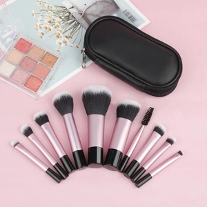 Flat lay of 10-piece portable makeup brush set with pink handles and black storage bag