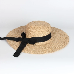 Detail of raffia sun hat with wide brim and elegant black ribbon bow accessory