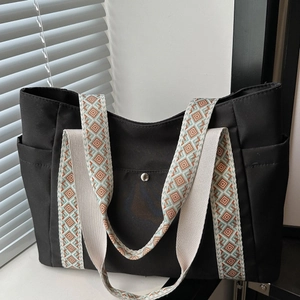Dettaglio borsa tote in nylon nero con tracolla in tela intrecciata a motivi etnici