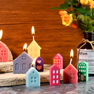 Detailed view of colorful mini house candles with intricate cutout windows on stone slab