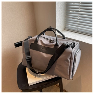Grey nylon fitness travel bag with black leather handles and shoulder strap on chair