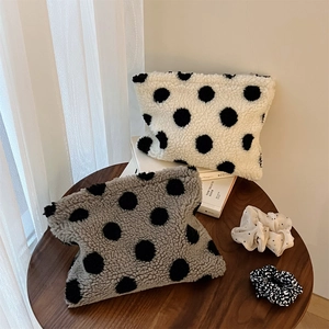 Polka dot faux lamb wool cosmetic bags in black and white on a wooden table