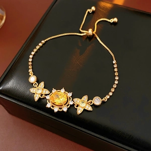 Detailansicht des goldenen Blumenarmbands mit gelben Edelsteinen auf schwarzer Box