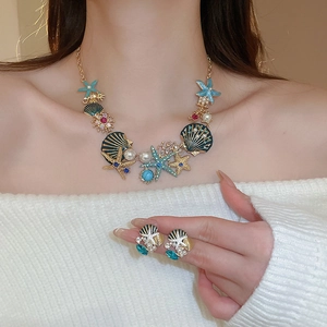 Detail view of ocean-themed necklace and earrings with starfish, shells, and pearls