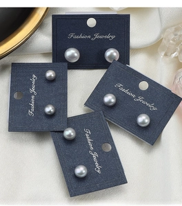 Detailed view of gray bread-shaped pearl earrings on blue display cards over white silk