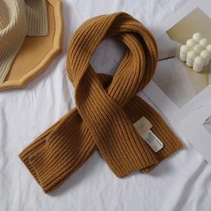Nahaufnahme des ingwergelben Strickschals mit Streifenmuster und Pflegeetikett