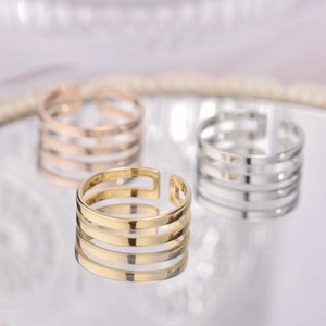 Three multi-layer adjustable rings in gold, silver, and rose gold on reflective mirror