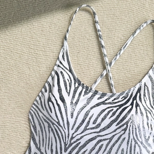 Close-up of zebra print swimsuit with silver glitter texture and cross back strap detail