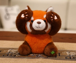 Detailed view of soft red panda plush toy in hide-and-seek pose with clover embroidery