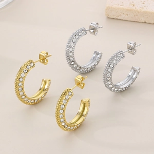 Detailed view of C-shaped 18k gold and silver earrings with micro-pave crystals