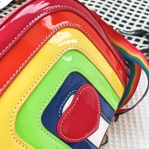 Detail of heart-shaped rainbow crossbody bag featuring layered patent leather and stitching