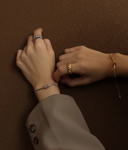 Macro shot of gold and silver chunky ribbed rings and knot bracelets on model's hand