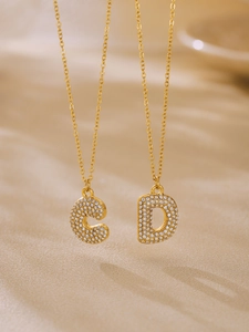 Detail of 18k gold plated necklaces with zircon-encrusted letter C and D pendants