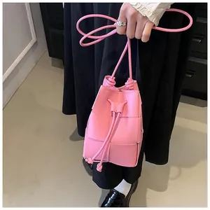 Detail of pink woven leather bucket bag featuring intricate Intrecciato craft and drawstring