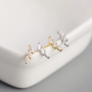 Close-up of gold and silver S925 studs with marquise zircons on white ceramic