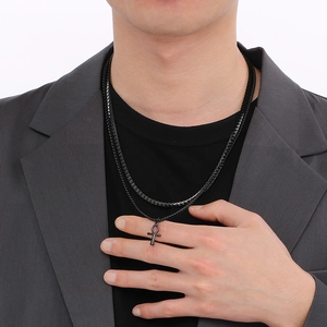 Close-up of men's double-layered black necklace featuring ankh cross pendant on model