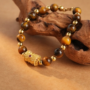 Macro shot of tiger eye stone beads and gold cylinder charm on vintage wooden branch