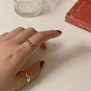 Close-up of a minimalist 925 sterling silver ring set on hand with aesthetic background