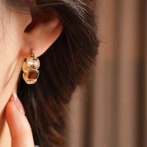 Close-up of vintage gold U-shaped earrings with champagne zircons worn by a model