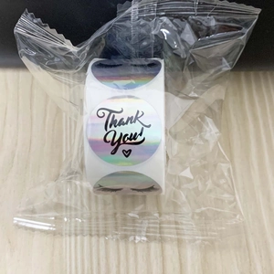 Macro shot of 3.8cm rainbow holographic Thank You stickers on a roll with heart design