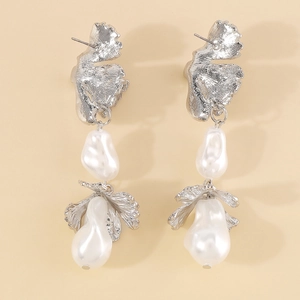 Detailed view of silver irregular metal petals and white baroque pearls on dangle earrings
