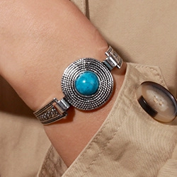 Close-up of vintage metal cuff featuring a turquoise stone and ethnic dot patterns