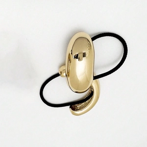 Close-up of sleek gold U-shaped metal buckle on black elastic ponytail holder