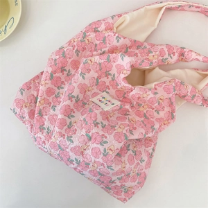 Close-up of pink floral shoulder bag with quilted bear texture and brand logo label
