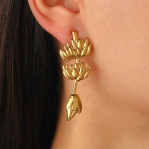 Détail de longues boucles d'oreilles pendantes dorées au design de grappe de bananes