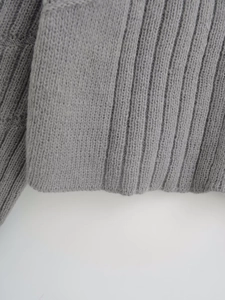 Detailed macro view of the grey ribbed knit fabric texture on a long sleeve sweater