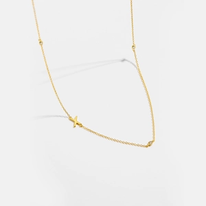 Macro detail of gold S925 sterling silver X pendant necklace with sparkling zircon accents